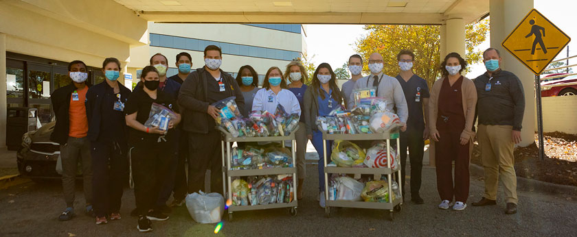 ACOM Students with donations pose outside of the ER entrance